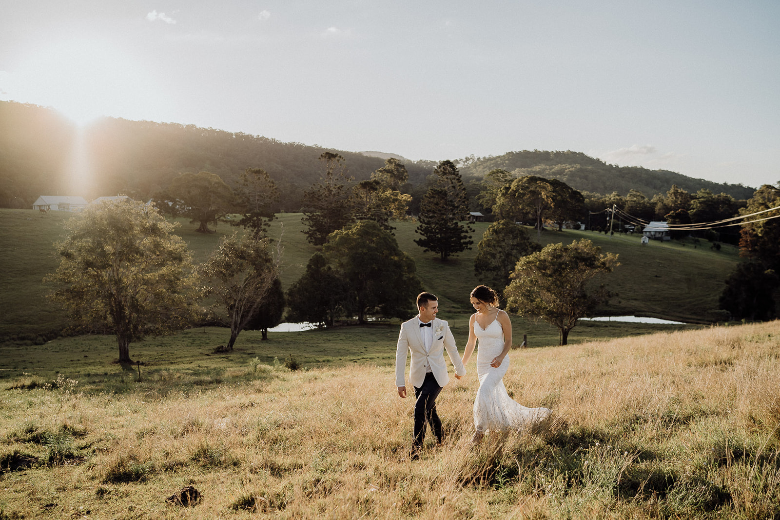 Bride and Groom walking through a paddock during sunset at during their Cowbell Creek Wedding Reception