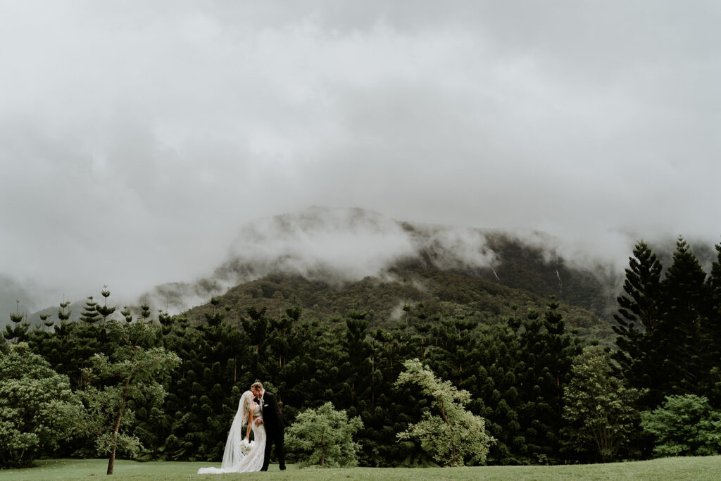 A couple walking the ground of The Bower Estate during their wedding with mountain ranges as a backdrop. 